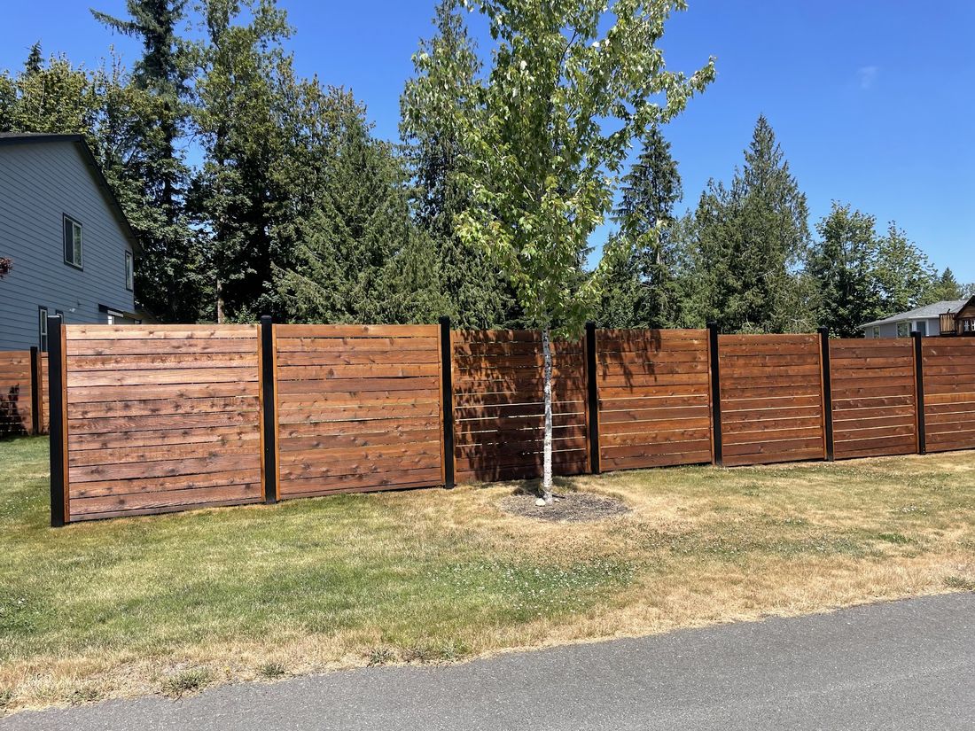 Horizontal-slat stained cedar fence along a street